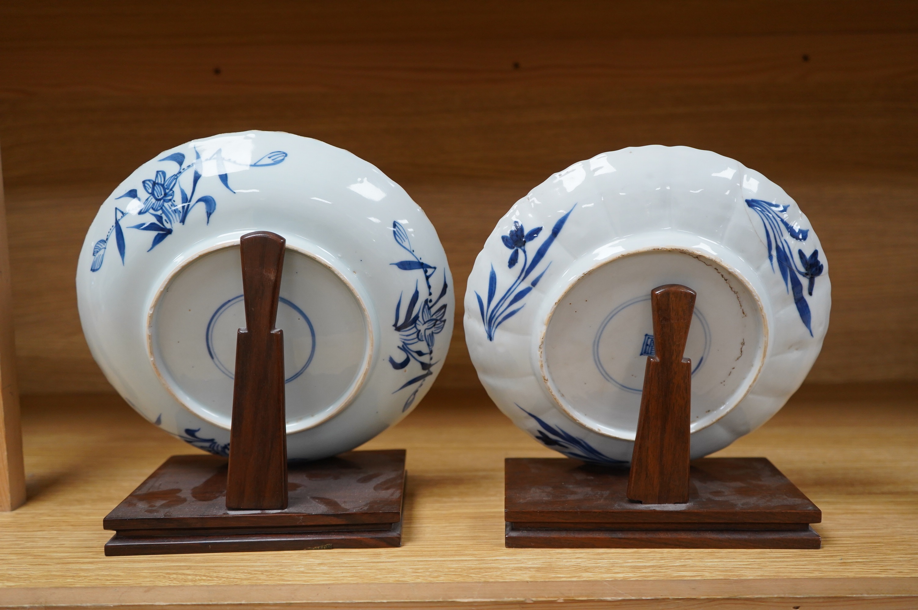 Two Chinese blue and white ‘astor’ plates, Kangxi period, with hardwood stands, largest 22cm diameter. Condition - poor to fair